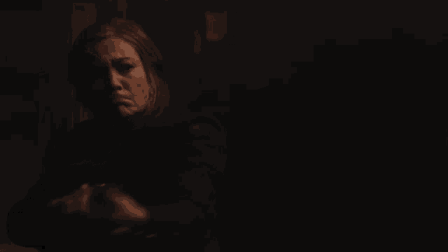a woman in a dark room holds a candle in her hand