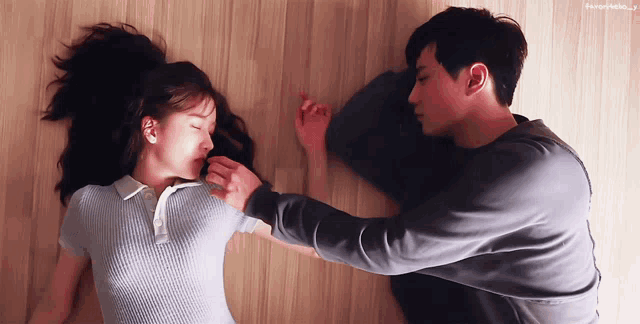a man and a woman are laying on a bed and the man is putting his hand on the woman 's shoulder