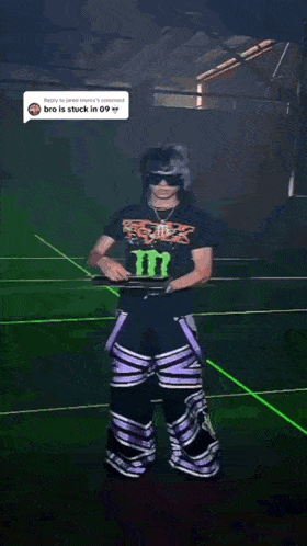 a man wearing a monster energy shirt is playing a keyboard