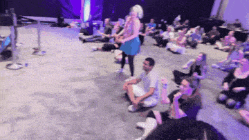 a woman in a blue dress is standing in front of a crowd of people