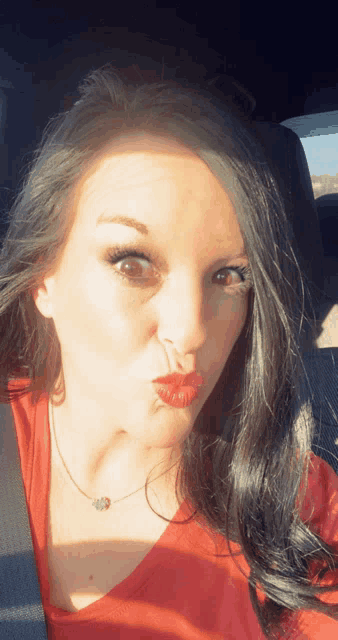 a woman wearing red lipstick is making a face in a car