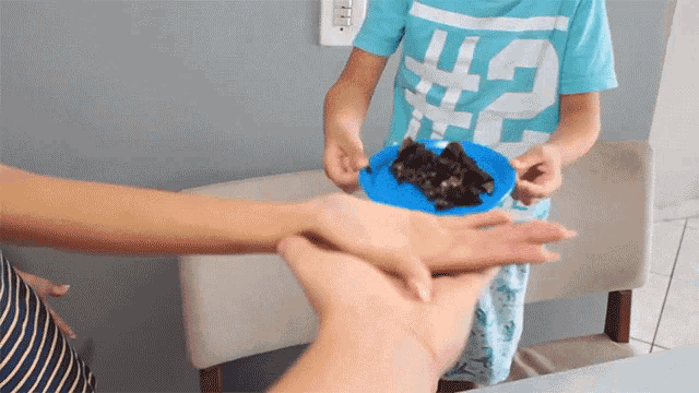 a boy wearing a # 2 shirt holds a blue plate with a piece of chocolate cake on it