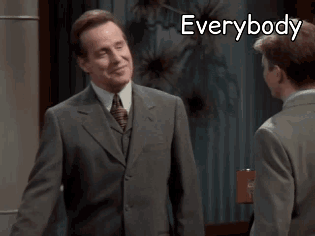 a man in a suit and tie talks to another man with the words everybody loves a cane