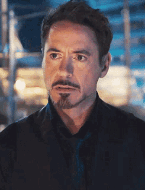 a man with a beard and mustache is wearing a black suit and tie