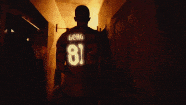 a man in a number 8 jersey stands in a hallway
