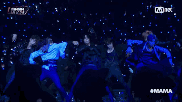 a group of people are dancing on a stage with the word mama on the bottom