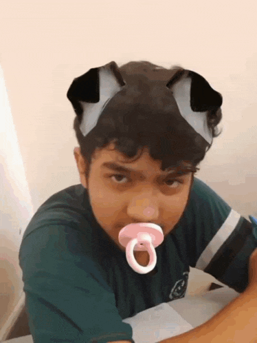 a boy with a pacifier in his mouth and a cat ear mask on his head