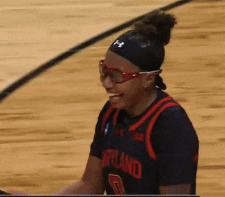 a woman wearing glasses and a maryland jersey smiles