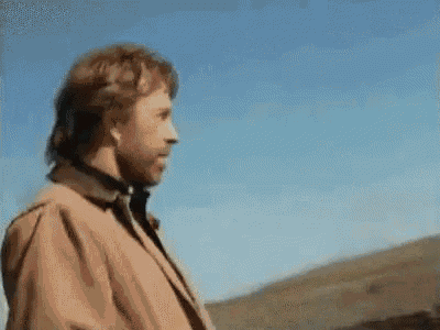 a man in a brown coat is standing in front of a mountain .