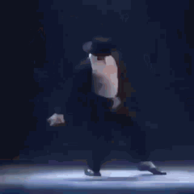 a man in a suit and hat is dancing on a stage .