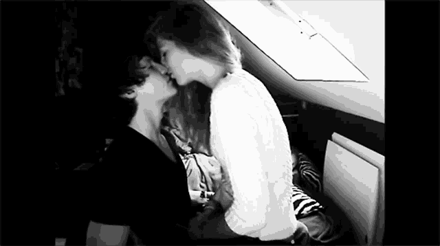 a black and white photo of a couple kissing