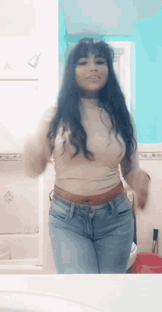 a woman is standing in front of a bathroom mirror wearing jeans and a turtleneck sweater .