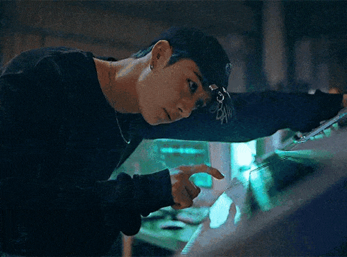 a man wearing a baseball cap is looking at a screen .