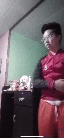 a man in a red jacket and orange pants stands in front of a dresser