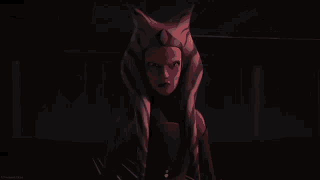 ahsoka tano from star wars is holding a lightsaber in her hands in a dark room .