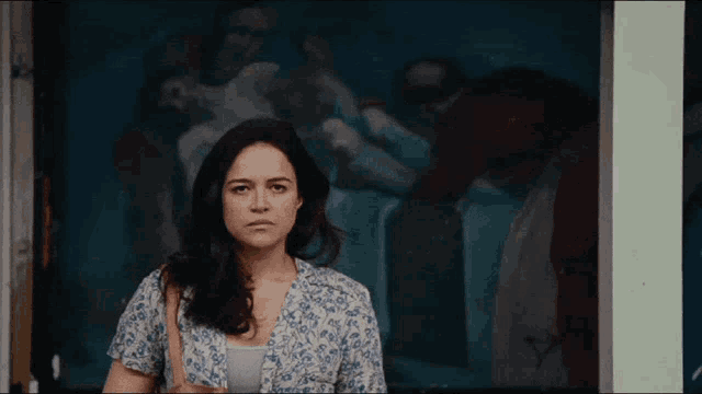a woman is standing in front of a painting that says ' a ' on it