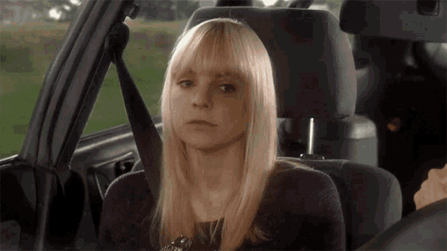 a woman is sitting in the back seat of a car with her seat belt on