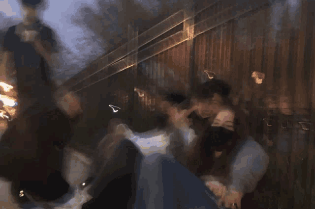 a blurry photo of people sitting in front of a wooden fence