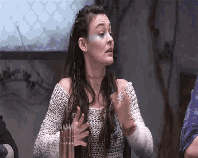 a woman in a white knitted sweater holds her hands out
