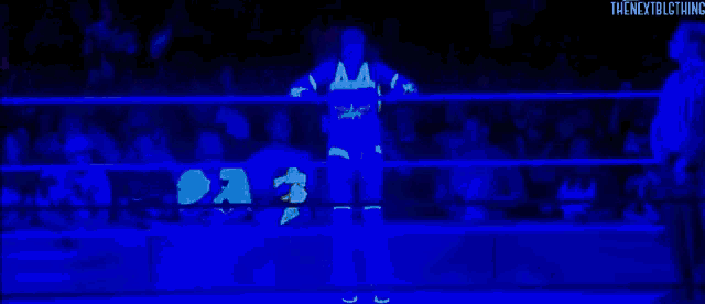 a glow in the dark wrestler is standing in a wrestling ring .