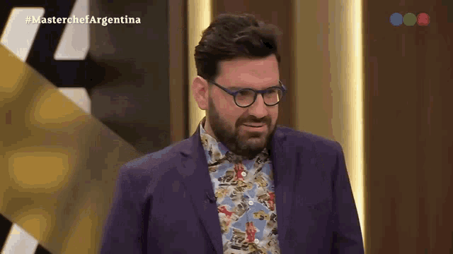 a man in a purple suit and glasses is on a television show called master chef argentina