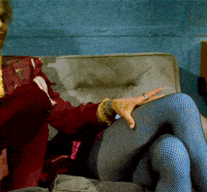 a woman in fishnet stockings sits on a couch with her legs crossed