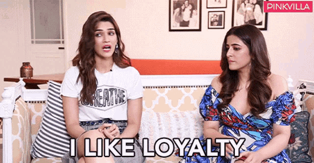 two women are sitting on a couch with the words i like loyalty written on the bottom