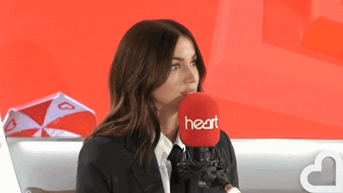 a woman talking into a microphone that says heart