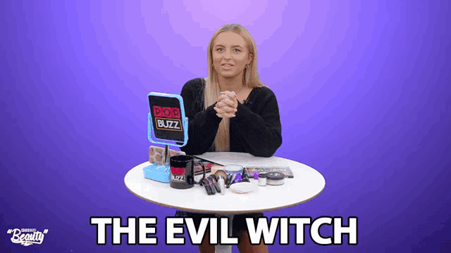 a woman is sitting at a table with makeup and a mug that says pop buzz