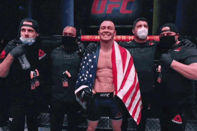 a man with an american flag wrapped around his shoulders stands in front of a ufc logo