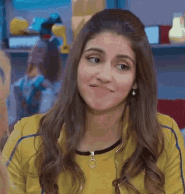 a woman is making a funny face while wearing a yellow shirt .