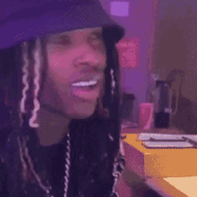 a man with dreadlocks is wearing a hat and holding a cell phone in his hand .