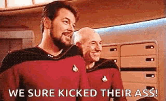 two men are standing next to each other on a star trek ship and one of them is saying `` we sure kicked their ass ! ''
