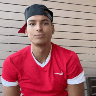 a young man wearing a red nike shirt and a hat