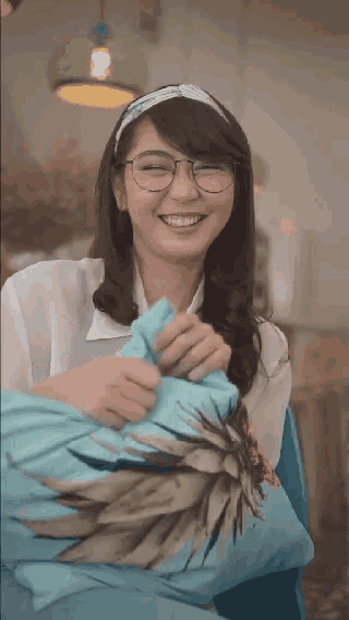 a woman wearing glasses is smiling while holding a pillow