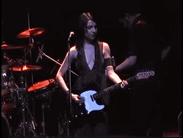 a woman is playing a guitar on a stage in front of a microphone .