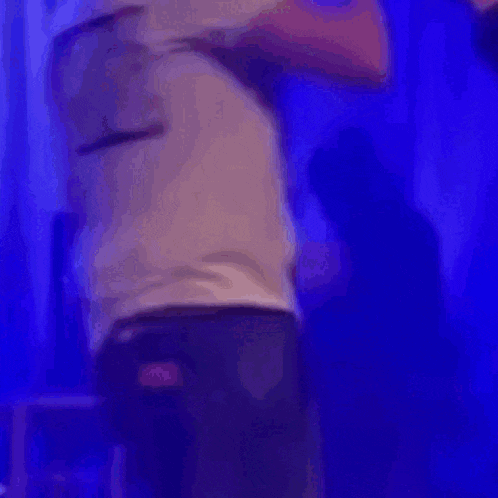 a man in a white shirt is standing on a stage in front of a blue light .