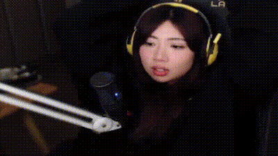a woman wearing headphones is sitting in a chair with her mouth open and a microphone .