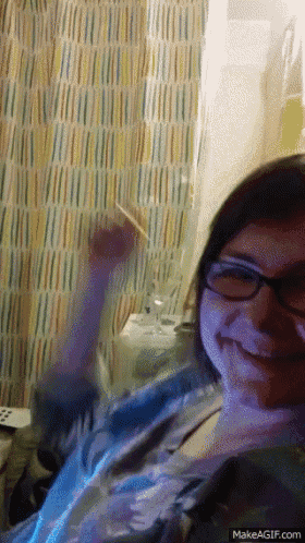 a woman wearing glasses is smiling and holding a glass of wine