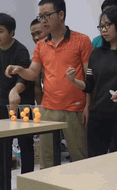 a group of people are playing a game with ping pong balls in cups