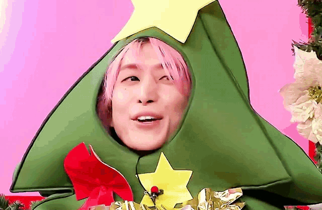 a man with pink hair is wearing a christmas tree costume
