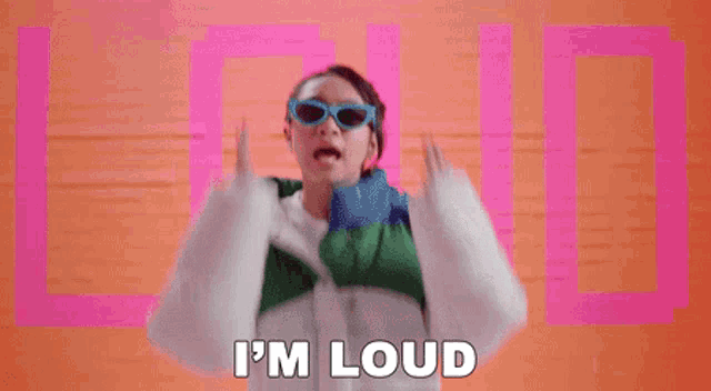 a woman wearing sunglasses and a jacket is making a funny face and says `` i 'm loud '' .