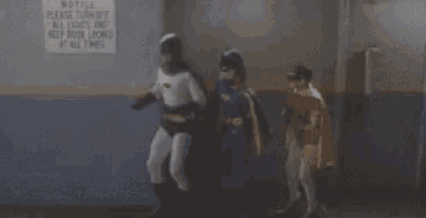 batman and batgirl are standing next to each other in front of a sign that says `` all lights and door locked at all times ''