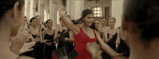 a woman in a red dress is dancing with a group of women