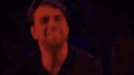 a man with a beard is making a funny face in a red light .