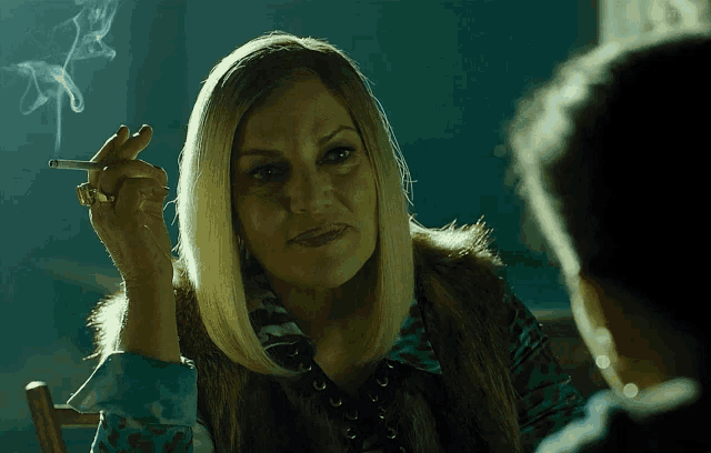 a woman is smoking a cigarette while sitting at a table