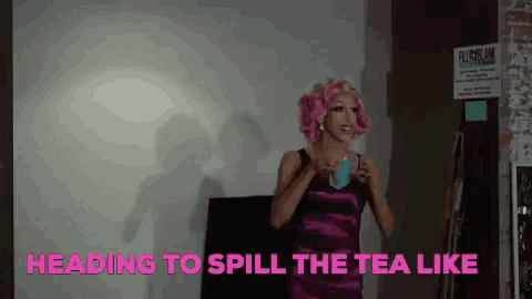 a drag queen is holding a cup of tea in front of a white board .