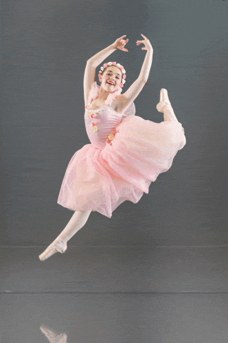a ballerina wearing a pink tutu and pointe shoes jumps in the air