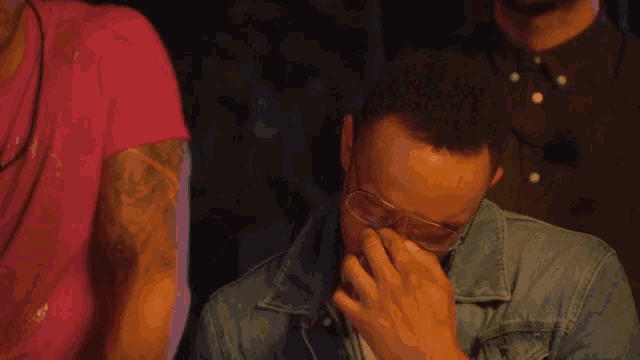 a man wearing glasses is being comforted by another man