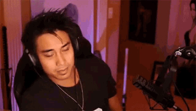 a man wearing headphones and a microphone is sitting in front of a microphone in a room .
